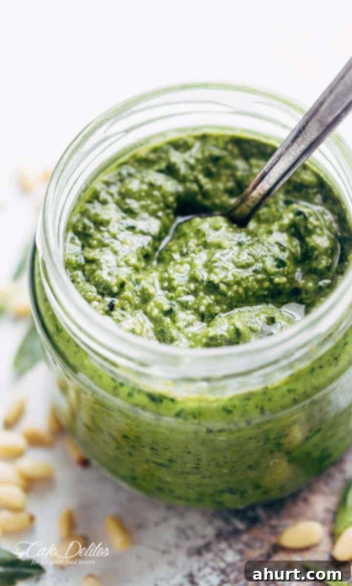 Freshly Made Basil Pesto Perfection 8 A jar of vibrant green basil pesto with a spoon dipped into it, ready to be served or stored.