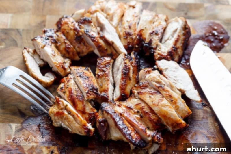 Slices of balsamic chicken resting on a cutting board, ready for the salad