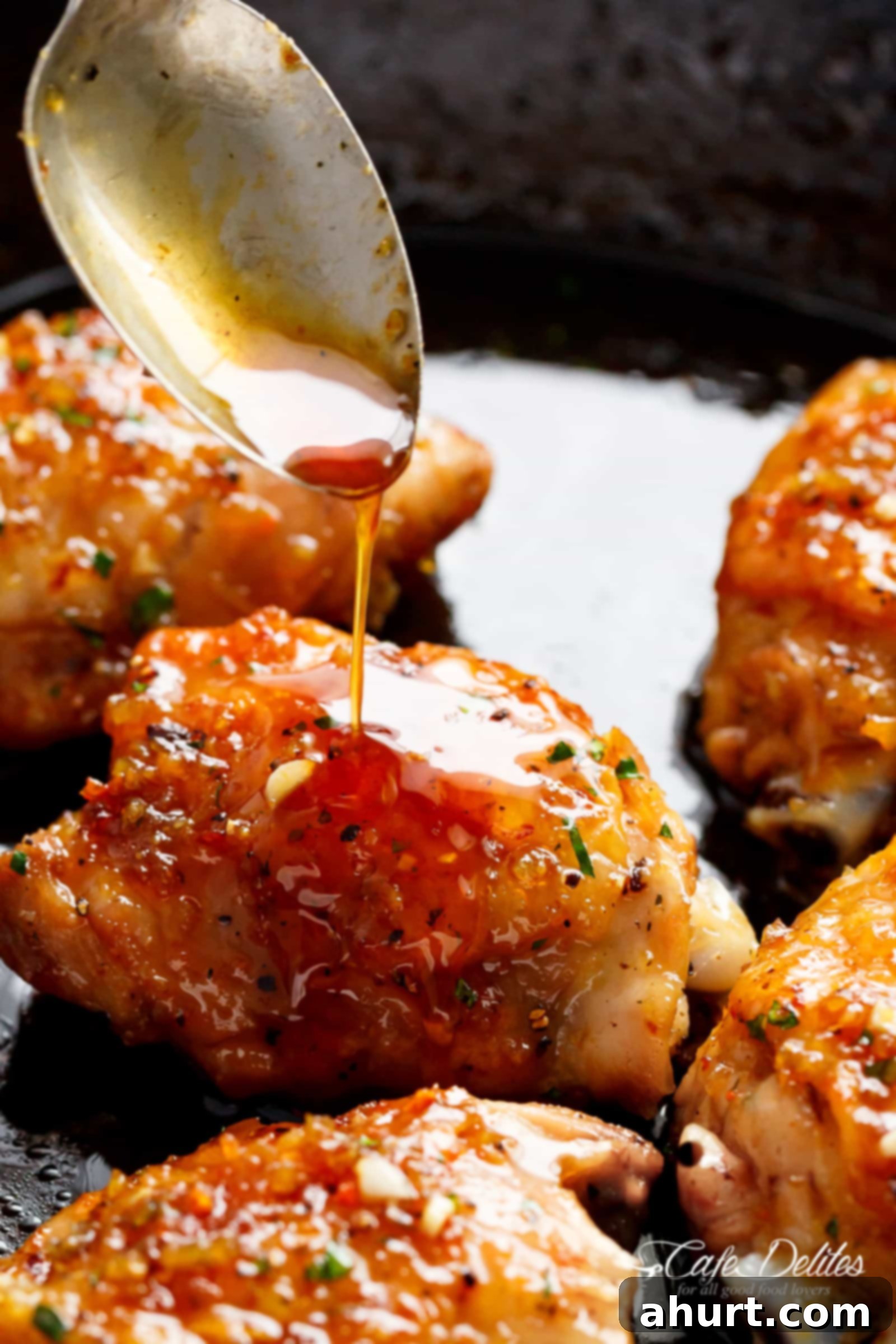 Sticky Honey Garlic Chicken 3 A silver spoon pouring sauce onto a crispy chicken thigh in a pan, looks delicious