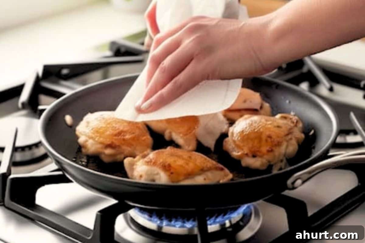 Blot the chicken thighs with paper towel and keep the pan on the heat.