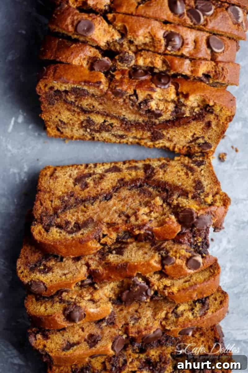 Nutella Pumpkin Chocolate Chip Bread slices arranged on a rustic wooden board, showcasing the rich chocolate chips and Nutella swirl within the moist pumpkin bread