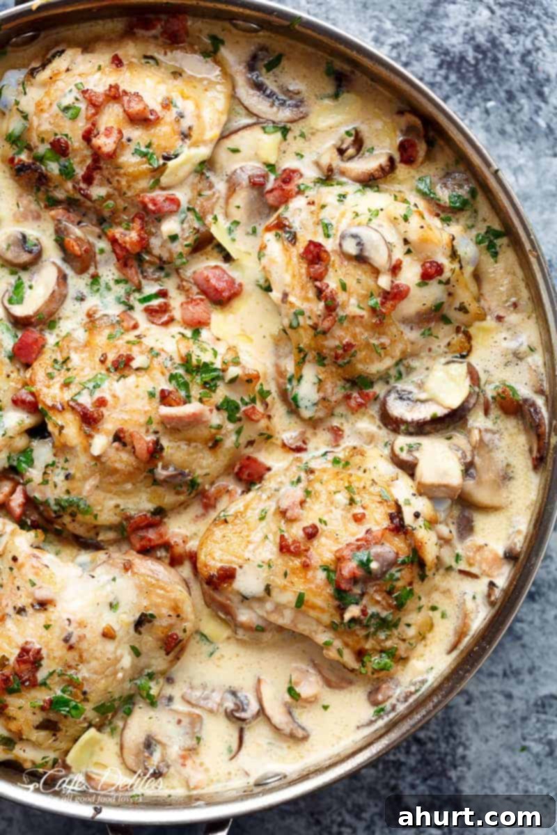 Creamy Baked Chicken Thighs with Mushrooms & Bacon in a mouthwatering cream sauce #bakedchickenthighs Creamy Garlic Parmesan Mushroom Chicken & Bacon in a pan, ready to serve.