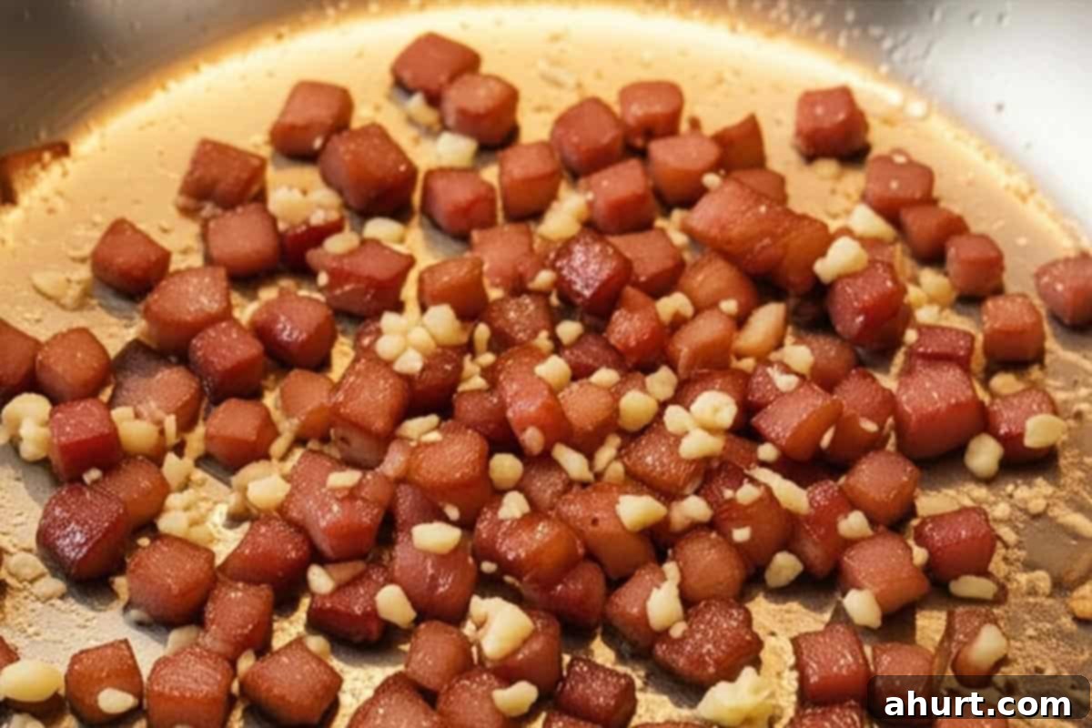 Luscious Creamy Garlic Parmesan Chicken 7 Diced bacon and minced garlic sizzling in a skillet with reserved chicken juices.