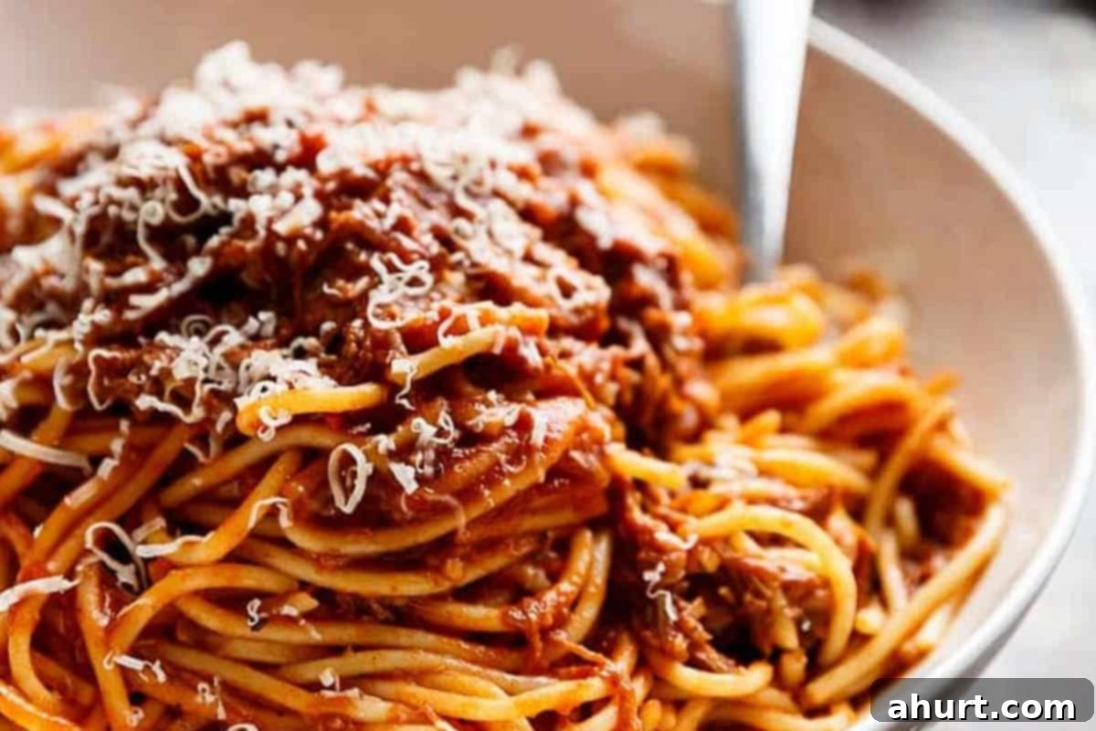 Fall-Apart Tender Slow Cooker Beef Ragu 11 Close-up shot of a bowl of Slow Cooker Beef Ragu, garnished with fresh herbs and a sprinkle of Parmesan cheese, highlighting its inviting texture and warmth.
