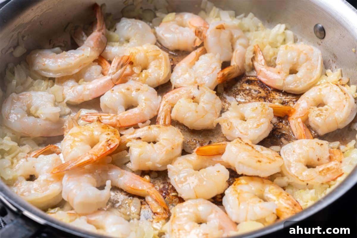 Velvety Tomato Garlic Butter Shrimp, Ready in 15 Minutes 6 Butter, onion, garlic, and raw shrimp being fried in a skillet with dried basil