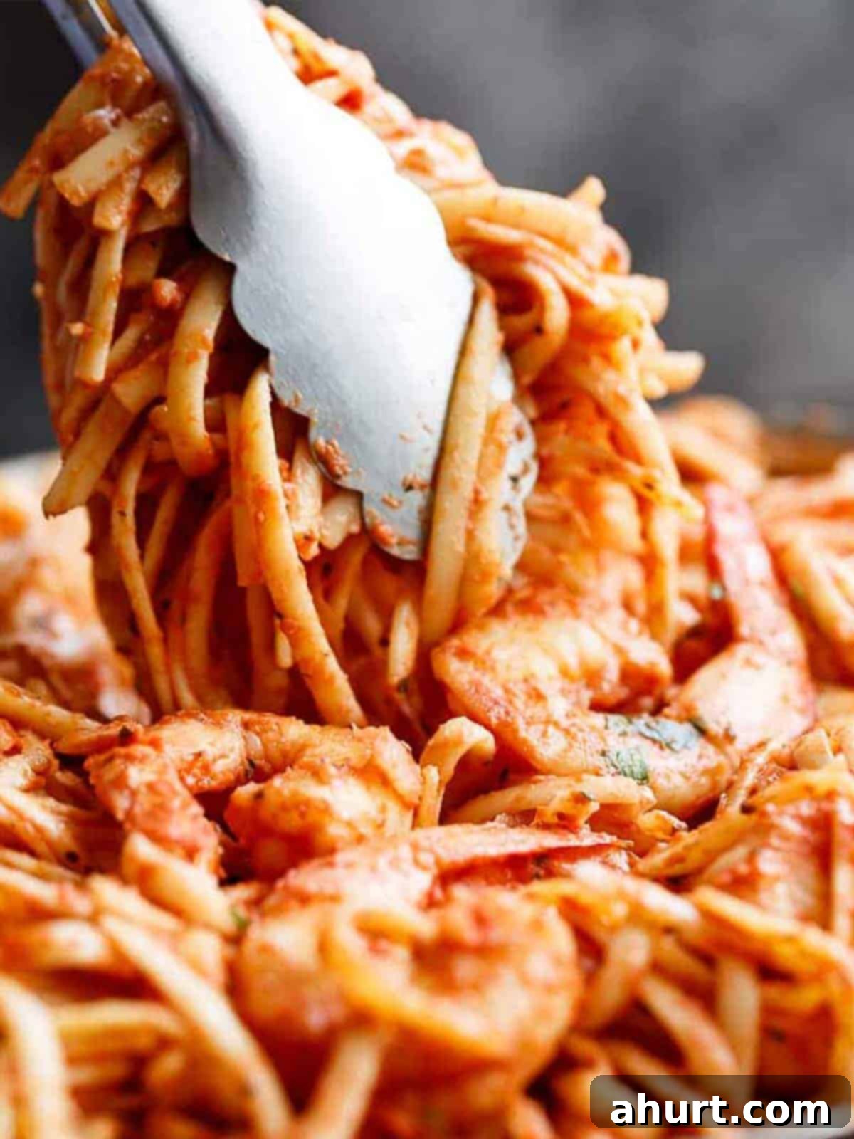 Velvety Tomato Garlic Butter Shrimp, Ready in 15 Minutes 10 Tongs holding up a portion of 15-Minute Creamy Tomato Garlic Butter Shrimp Pasta, showing the rich sauce and perfectly cooked shrimp, ready to be served