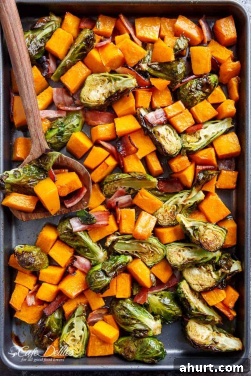 Honey Roasted Butternut Squash & Brussels Sprouts With Bacon on a baking tray, glistening with honey and bits of bacon