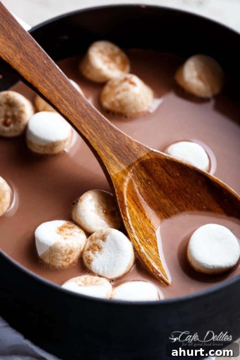Comforting Hot Chocolate 4 Marshmallows floating in a mug of creamy hot chocolate, with a spoon nearby.