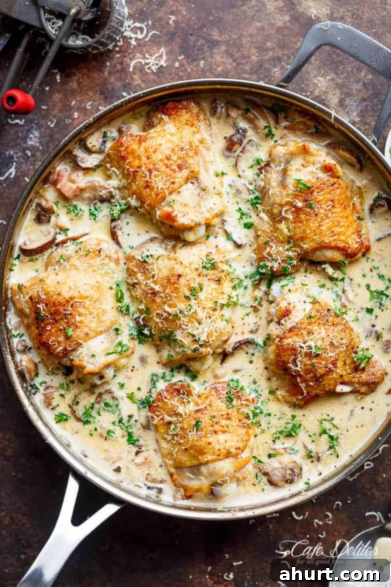 Overhead view of Creamy Parmesan Herb Mushroom Chicken simmering in a pan, showcasing the golden chicken and rich sauce
