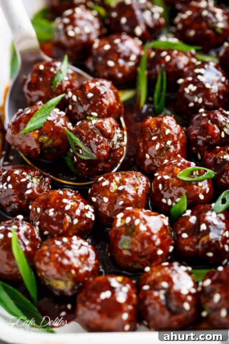 Sweet and Savory Mongolian Meatballs 3 A serving spoon filled with sticky, glossy Mongolian Glazed Meatballs, garnished with green onions.