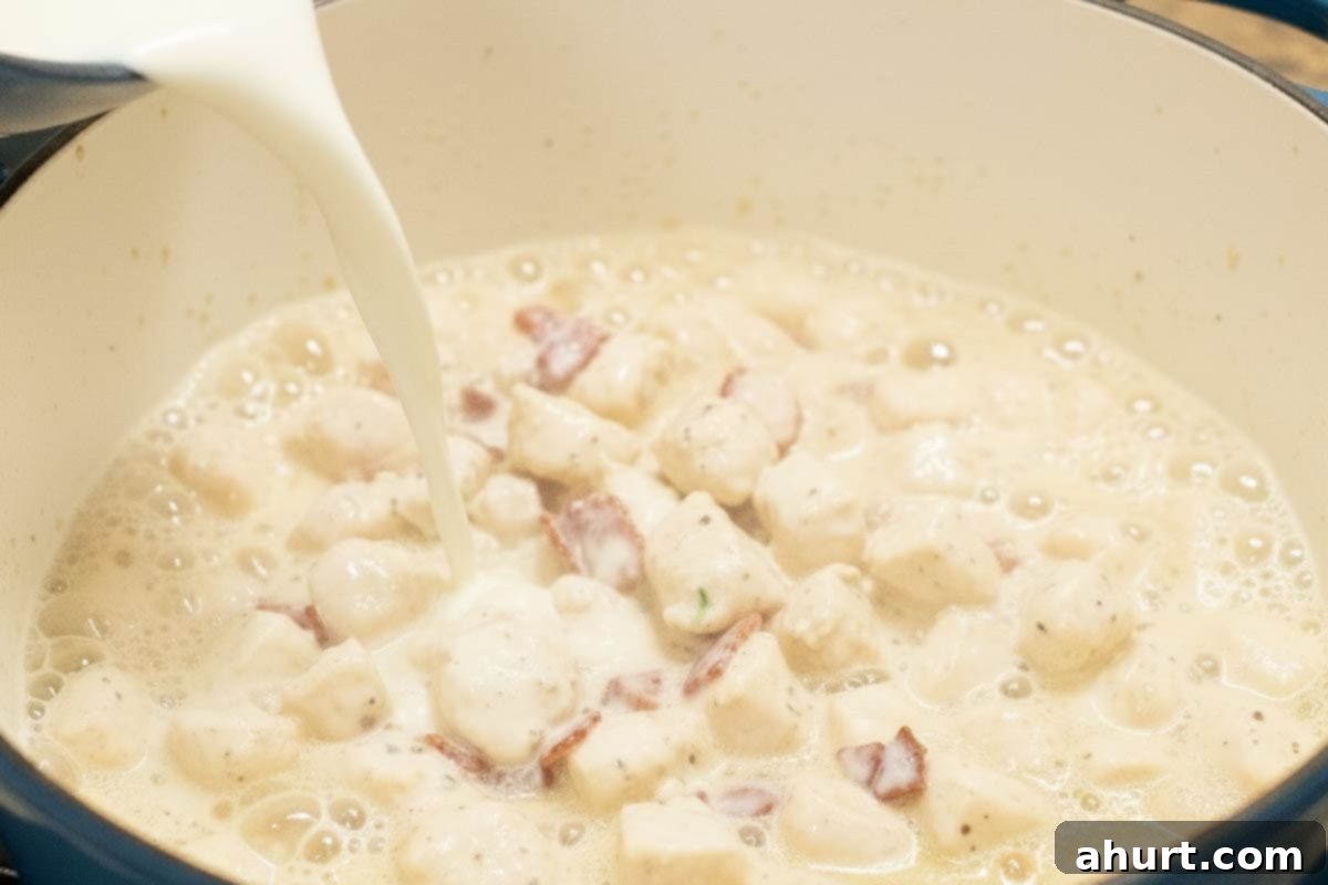 Easy One Pot Chicken Bacon Fettuccine Alfredo 7 Pouring fresh milk into the pot with chicken, bacon, and seasonings, preparing for the pasta to be added.