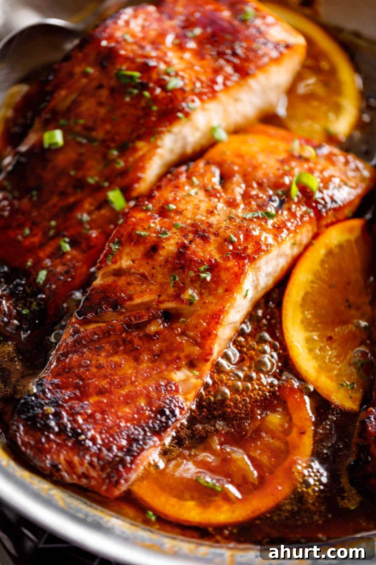 Crispy Honey Orange Glazed Salmon on a skillet, beautifully seared and coated in sauce.