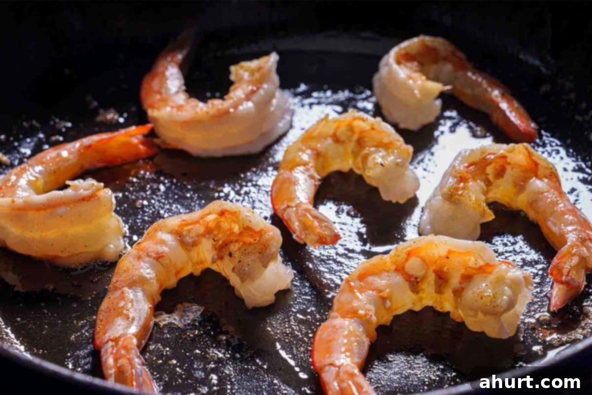 Creamy Tuscan Garlic Butter Shrimp 4 Image of shrimp being cooked over medium heat in a skillet with garlic.