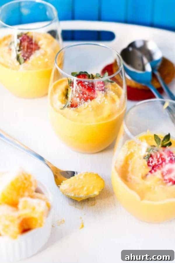 Three elegant glasses filled with creamy, vibrant Mango Coconut Cheesecake Parfaits, ready to be enjoyed.