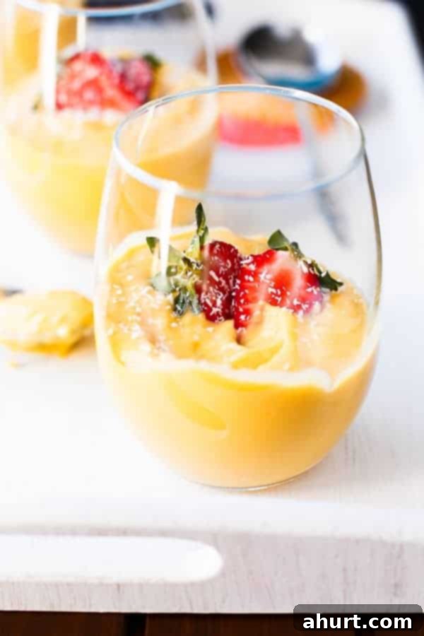 Side view of a glass filled with a delightful Mango Coconut Cheesecake Parfait, showcasing the layers and creamy texture.