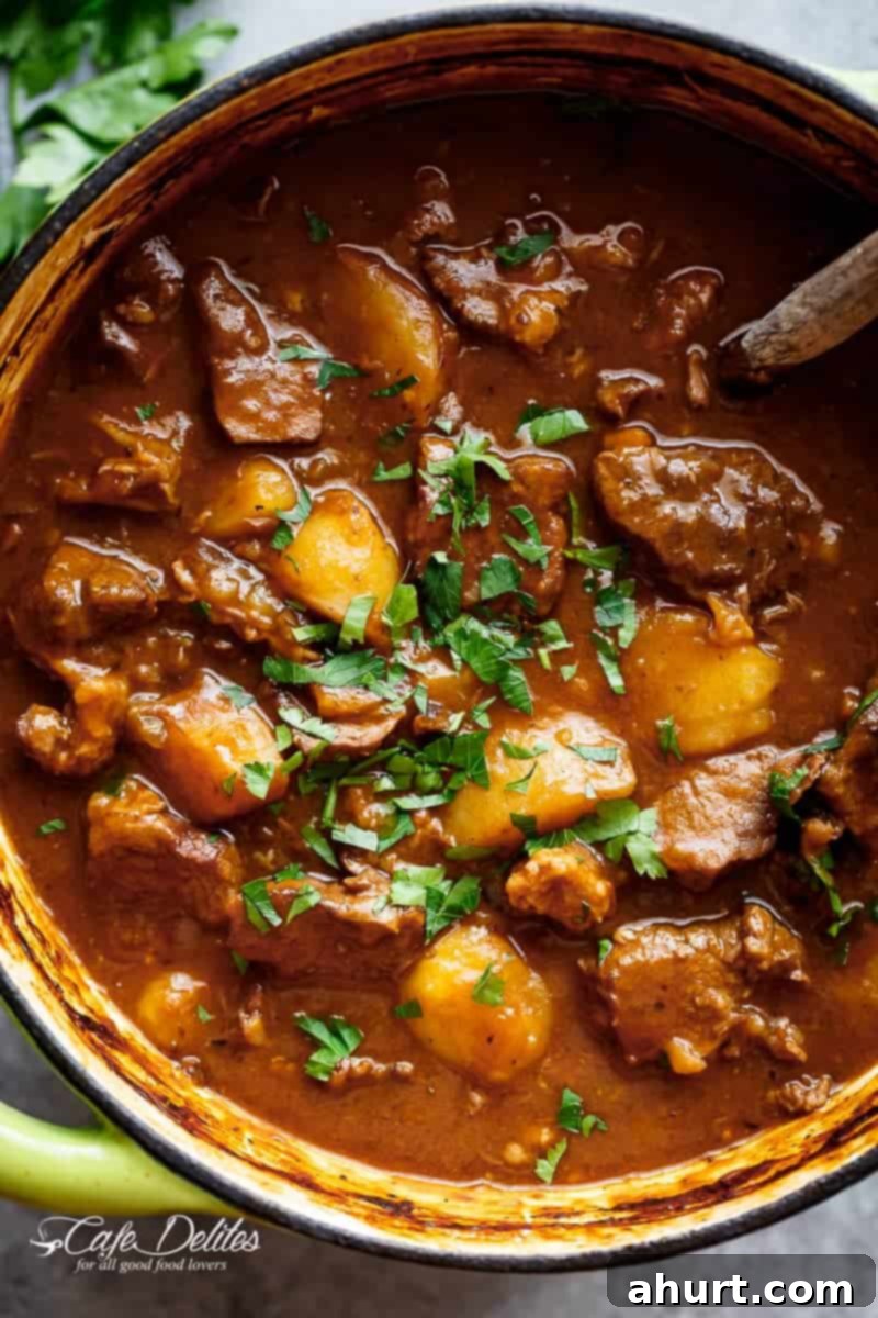 Hearty Guinness Beef Stew 2 Top view image of a hearty Beef And Guinness Stew in a large pot with crusty bread