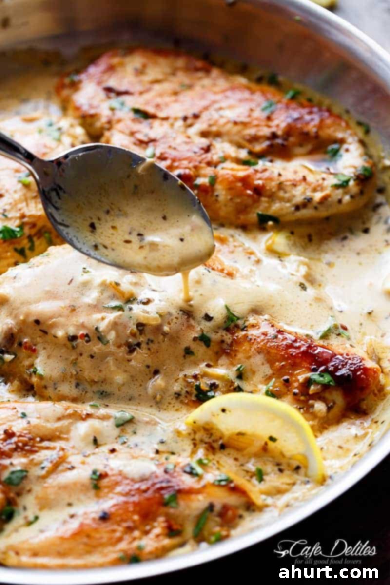 Thick, luscious cream sauce being poured over perfectly grilled chicken pieces in a large pot, highlighting the sauce's rich consistency.