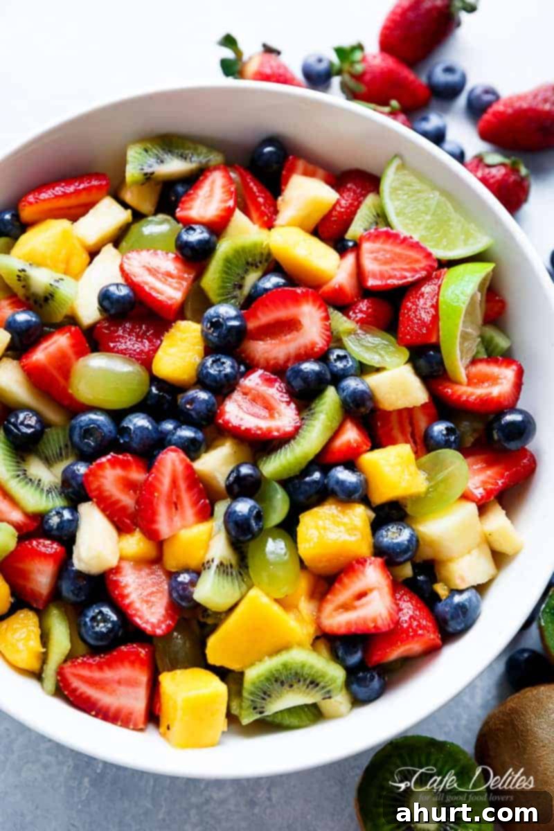 Sweet and Tangy Honey Lime Fruit Salad 2 Top view of vibrant Honey Lime Fruit Salad with mixed berries, kiwi, and mango in a white bowl, garnished with mint.