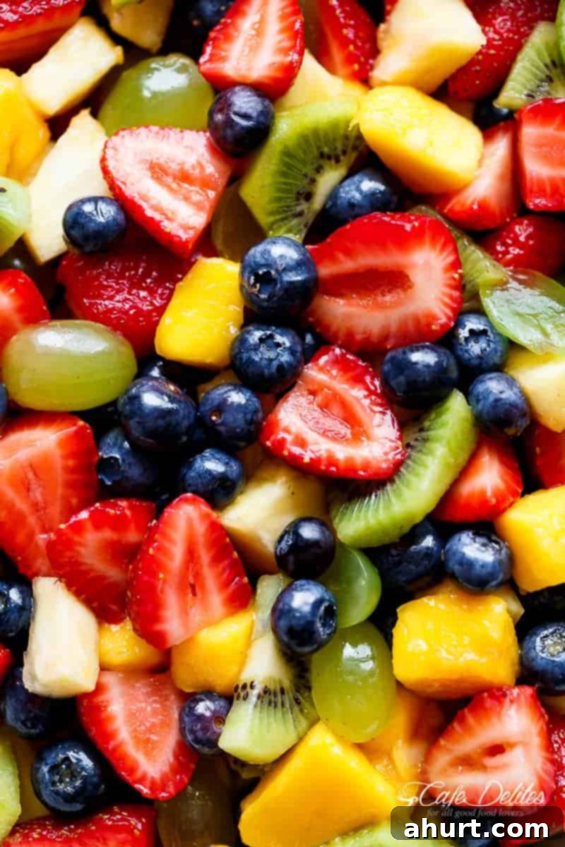 Sweet and Tangy Honey Lime Fruit Salad 3 Close-up of fresh Honey Lime Fruit Salad showcasing juicy strawberries, blueberries, kiwi, and mango pieces with a glossy dressing.