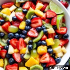 Sweet and Tangy Honey Lime Fruit Salad 5 Honey Lime Fruit Salad in a white serving bowl, topped with fresh mint.