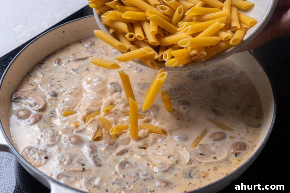 One-Pot Creamy Mushroom Chicken Pasta 6 creamy mushroom sauce with penne being poured in