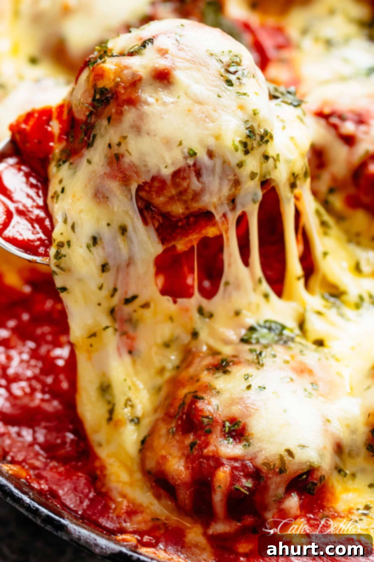 Cheesy Meatballs with melted mozzarella cheese over spaghetti #cafedelites #dinner #meatball #recipe #sauce #cheese #mozzarella A piece of Cheesy Meatballs taken out from the bowl