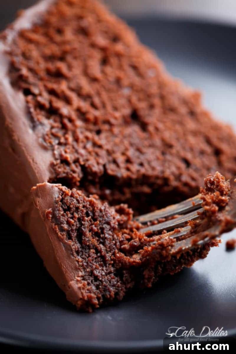 Decadently Fudgy Chocolate Cake 4 A fork pierced into a slice of Fudgy Chocolate Cake, highlighting its moist and dense texture.