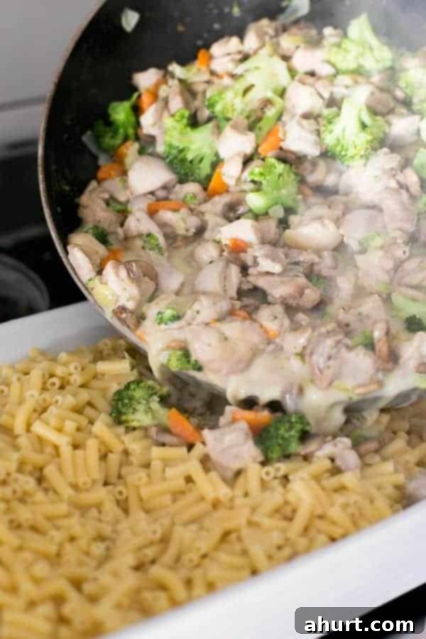 Creamy Chicken and Mushroom Cheese being poured over boiled Macaroni in a bowl