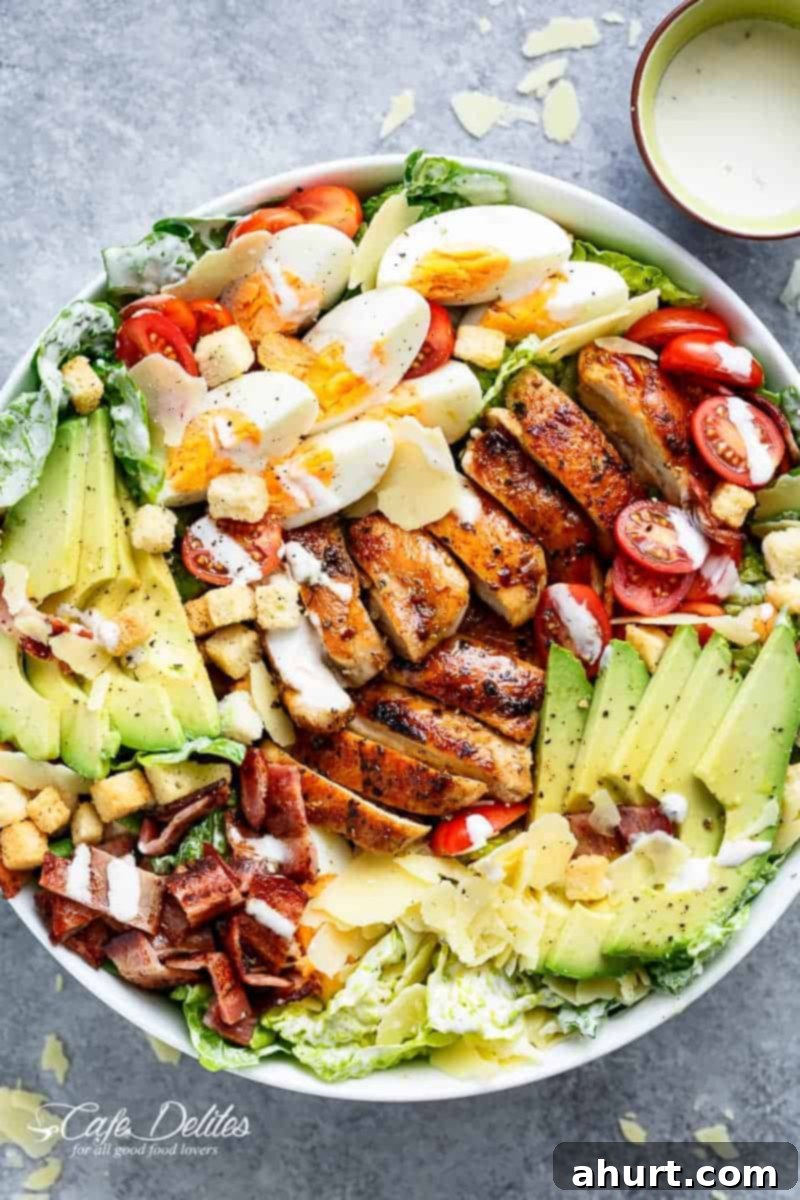 A vibrant and generously portioned Grilled Chicken Cobb Caesar Salad, showcasing all its delicious components. Perfect for a satisfying meal.