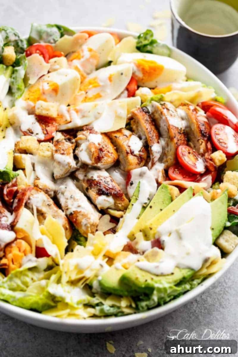 A large, inviting bowl of Grilled Chicken Cobb Caesar Salad, beautifully arranged and ready for serving.