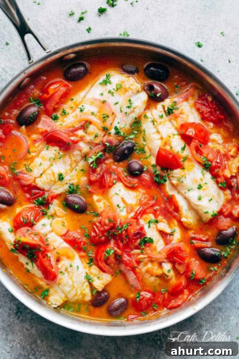 Pan Seared Fish With Tomatoes & Olives in a pan, showcasing the golden-brown fish fillets and vibrant sauce