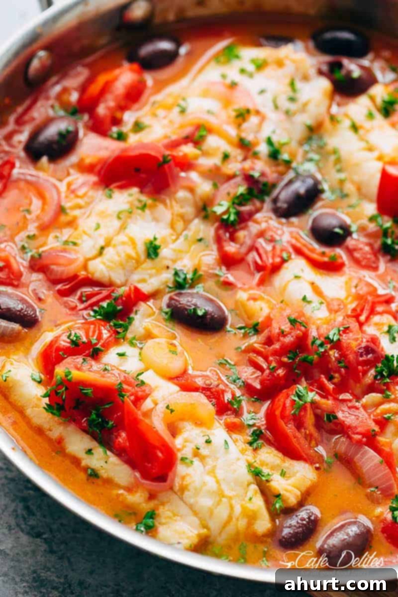 Super zoomed-in image of Pan Seared Fish With Tomatoes & Olives, showing the fresh herbs and rich sauce