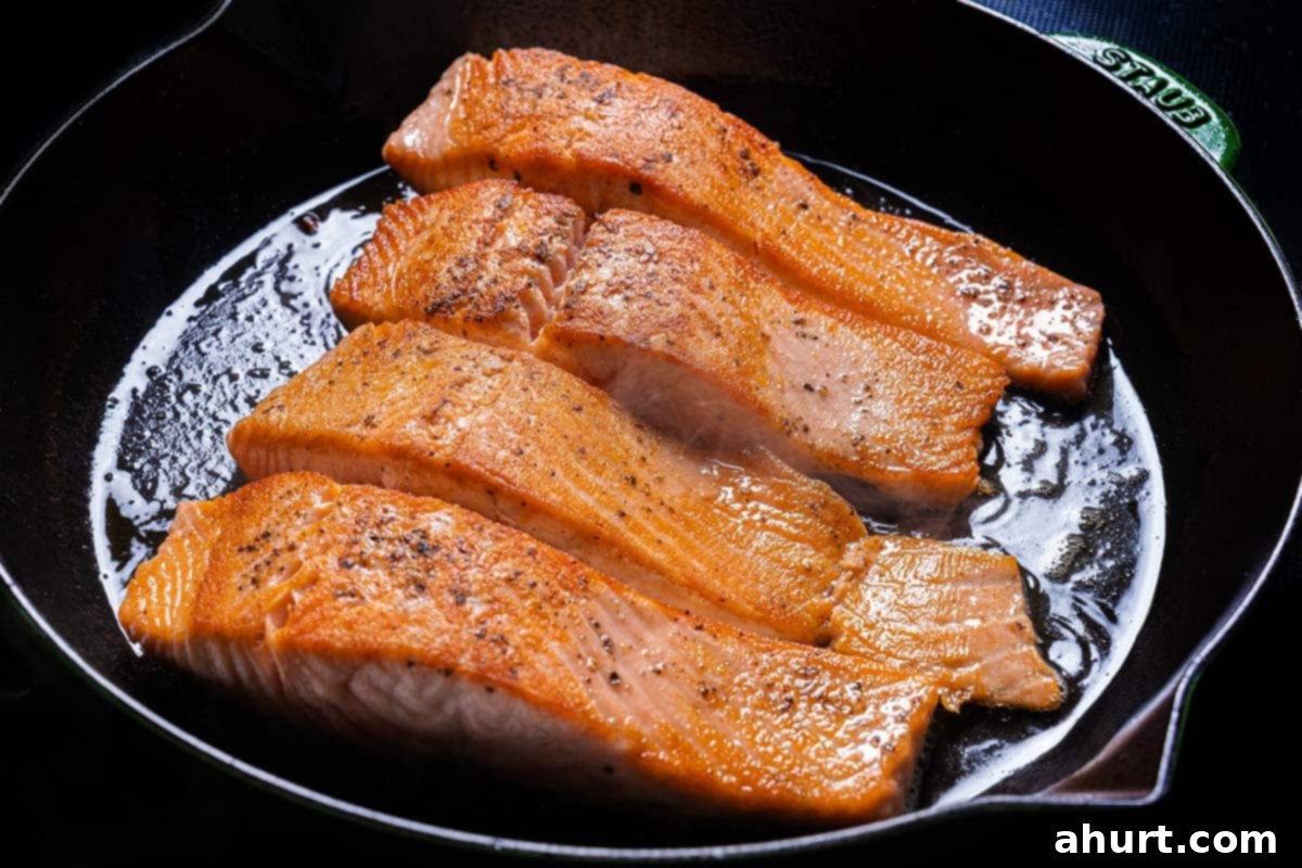 Velvety Tuscan Garlic Butter Salmon 5 An image of salmon fillets being seasoned generously with salt and pepper, then placed flesh-side down into a hot pan for searing.