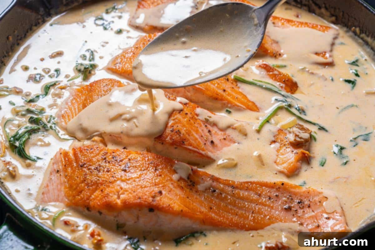 Velvety Tuscan Garlic Butter Salmon 9 Pan-seared salmon fillets are carefully returned to the creamy Tuscan sauce, ready to be coated and served with fresh parsley.