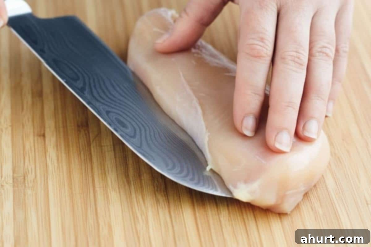 Velvety Chicken Francese 4 Slicing a raw chicken breast in half horizontally to create thinner cutlets for Chicken Francese.