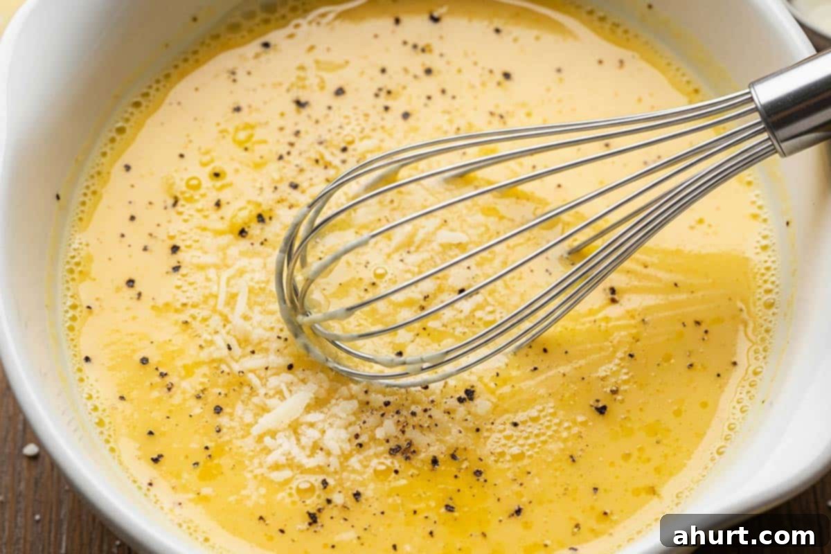 Velvety Chicken Francese 5 A shallow bowl with whisked eggs, parmesan cheese, lemon juice, salt, and black pepper for the chicken coating for Creamy Chicken Francese.