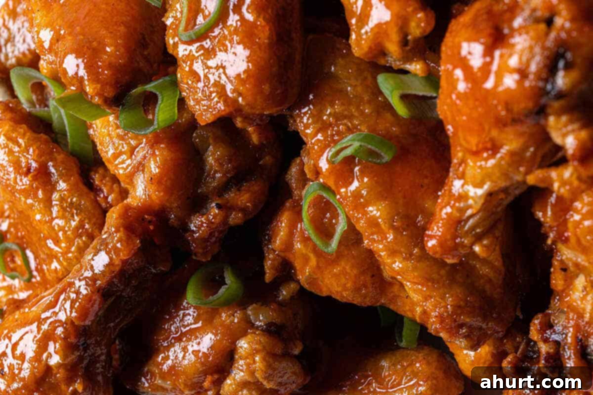 Golden Crisp Baked Buffalo Wings 11 A plate of freshly baked buffalo wings, coated in sauce, with celery sticks and a bowl of blue cheese dressing on the side.