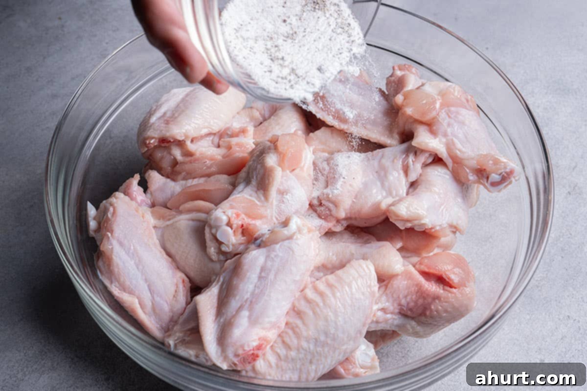 Golden Crisp Baked Buffalo Wings 6 Chicken wings in a bowl being tossed with a mixture of baking powder, garlic powder, salt, and pepper.