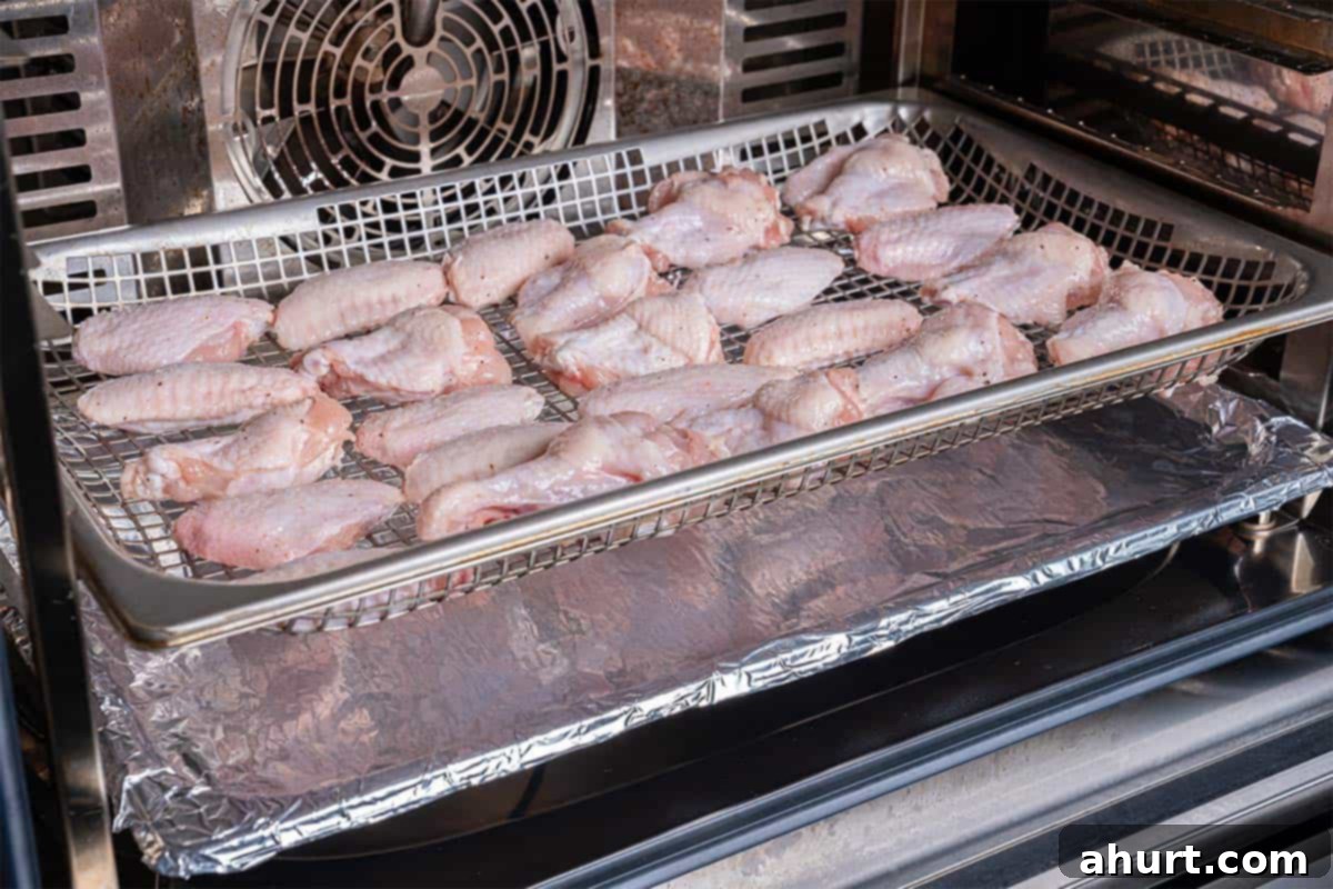 Golden Crisp Baked Buffalo Wings 7 Seasoned chicken wings arranged in a single layer on a wire rack on a baking sheet, with space between each wing.