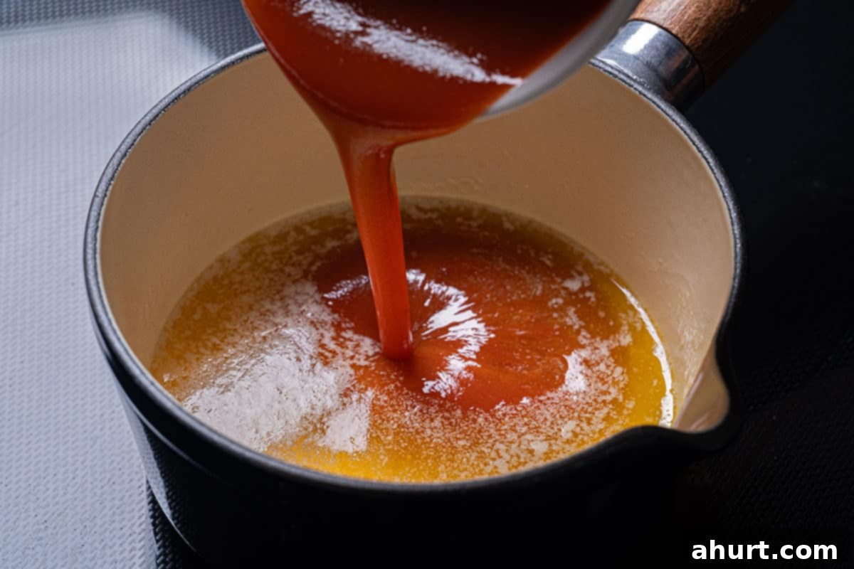 Golden Crisp Baked Buffalo Wings 9 Hot sauce, melted butter, and honey being whisked together in a bowl to create the buffalo sauce.