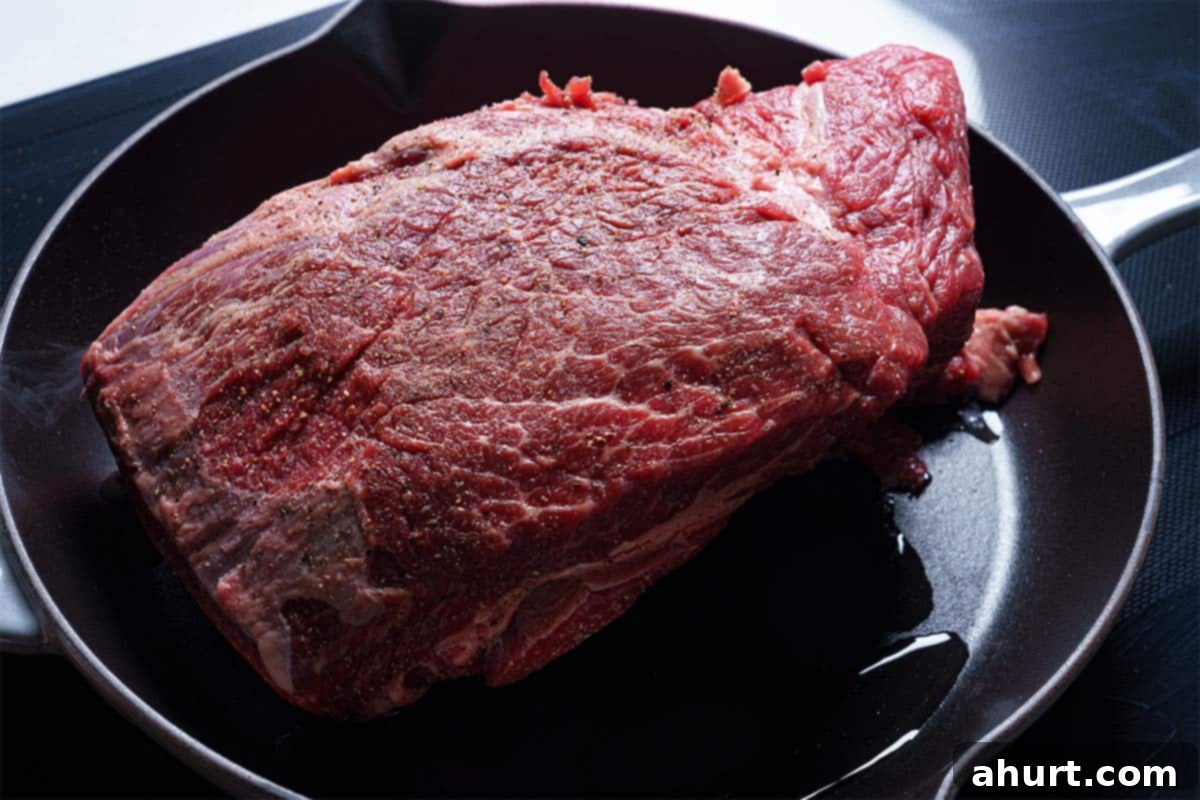 Melt In Your Mouth Pot Roast 4 An image of the beef seasoned with salt and pepper being transferred to the skillet to be seared.