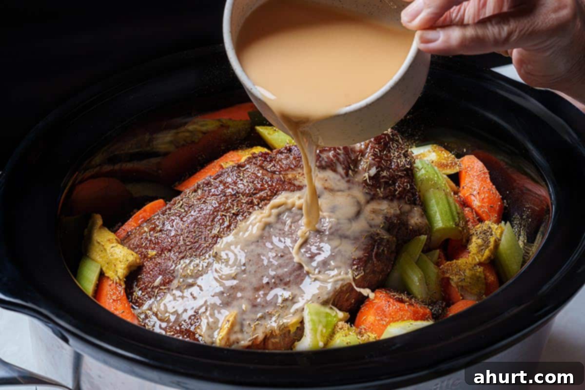 Melt In Your Mouth Pot Roast 6 An image of the chuck beef being placed into the slow cooker while being coated in sauce.