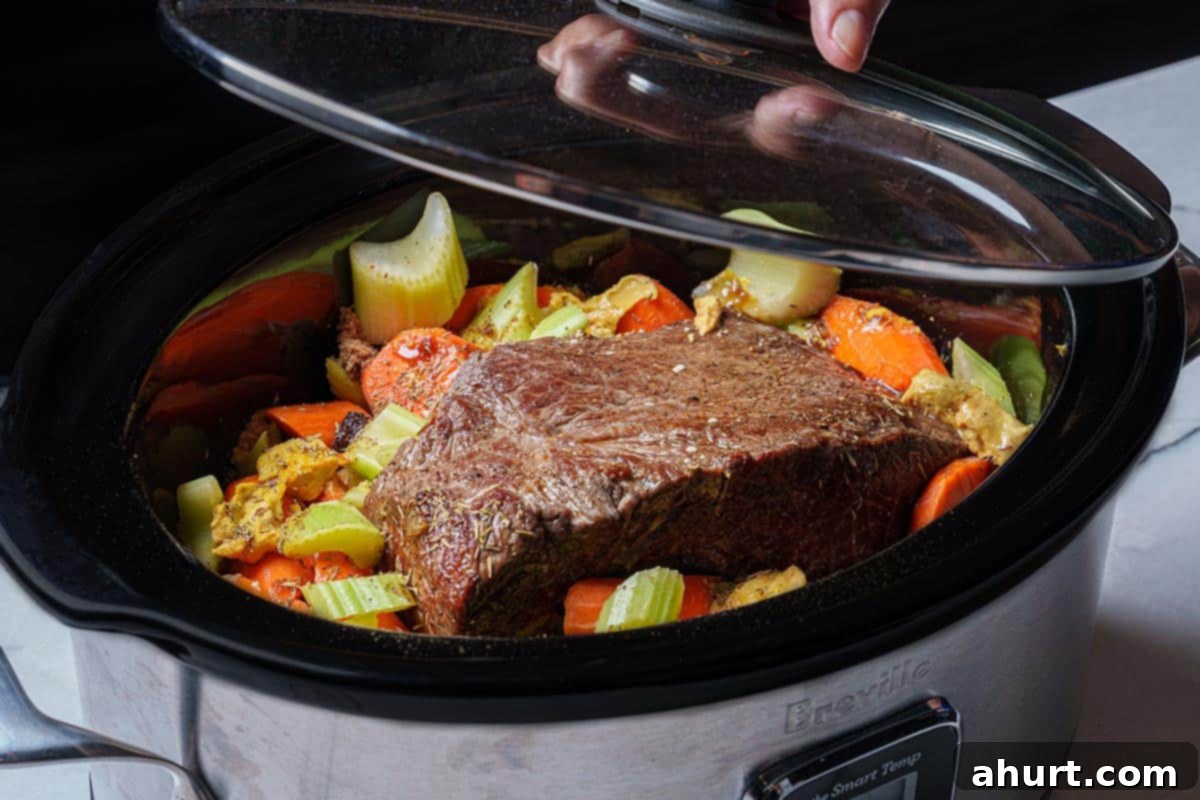 Melt In Your Mouth Pot Roast 7 An image of the slow cooker being cooked on low for 8 hours to tenderize the meat and soften the vegetables.