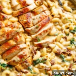 Hearty Tuscan Chicken Skillet Mac 13 Tuscan chicken sliced, on top of a bed of creamy pasta with sundered tomatoes and spinach with Fresh herbs sprinkled on top.