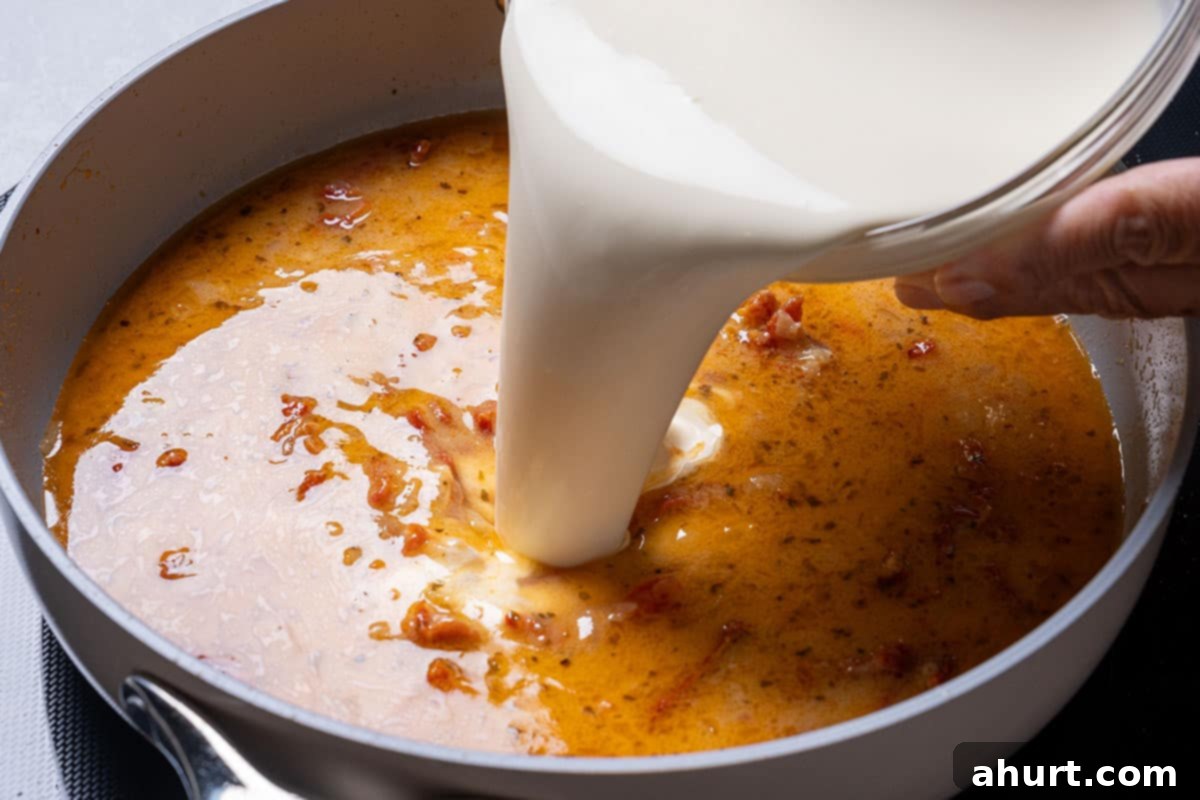 Hearty Tuscan Chicken Skillet Mac 8 Milk being poured into the pan to form the creamy sauce where the macaroni will cook to perfection.