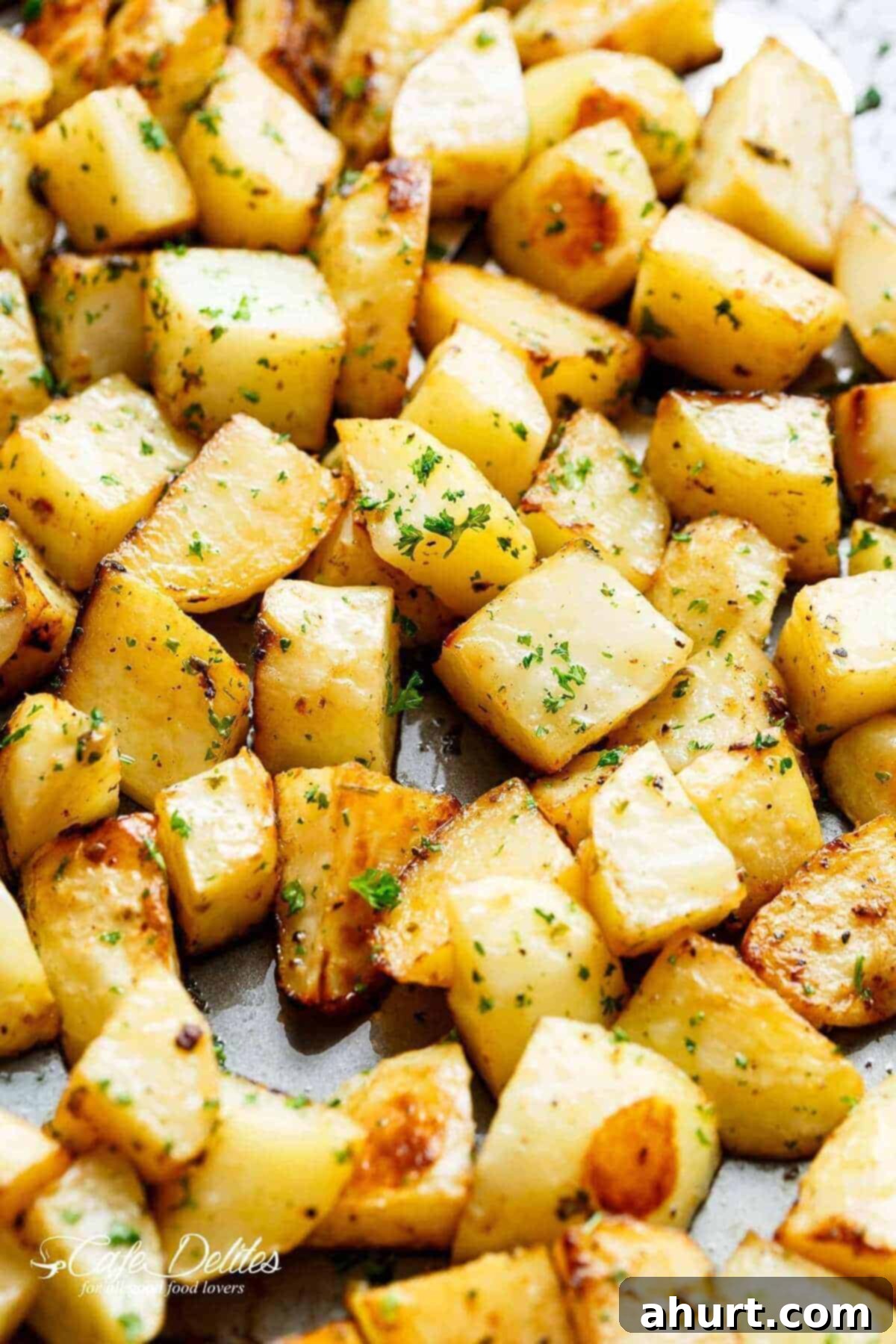 Golden Crispy Garlic Potatoes 2 Yummy Crispy garlic roasted potatoes sprinkled with fresh green herbs on a baking tray.