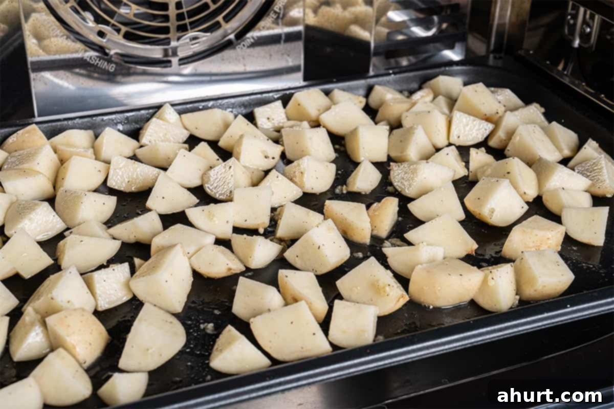 Golden Crispy Garlic Potatoes 6 Potatoes arranged on a baking tray being placed into the oven for roasting.