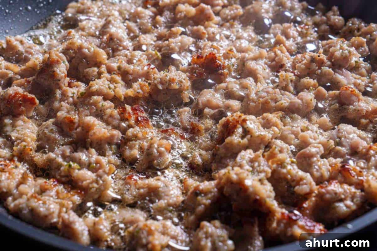 Irresistible Sausage Stuffing 5 Step 2: The image shows the sausage being sautéed and browned in a skillet over medium heat.