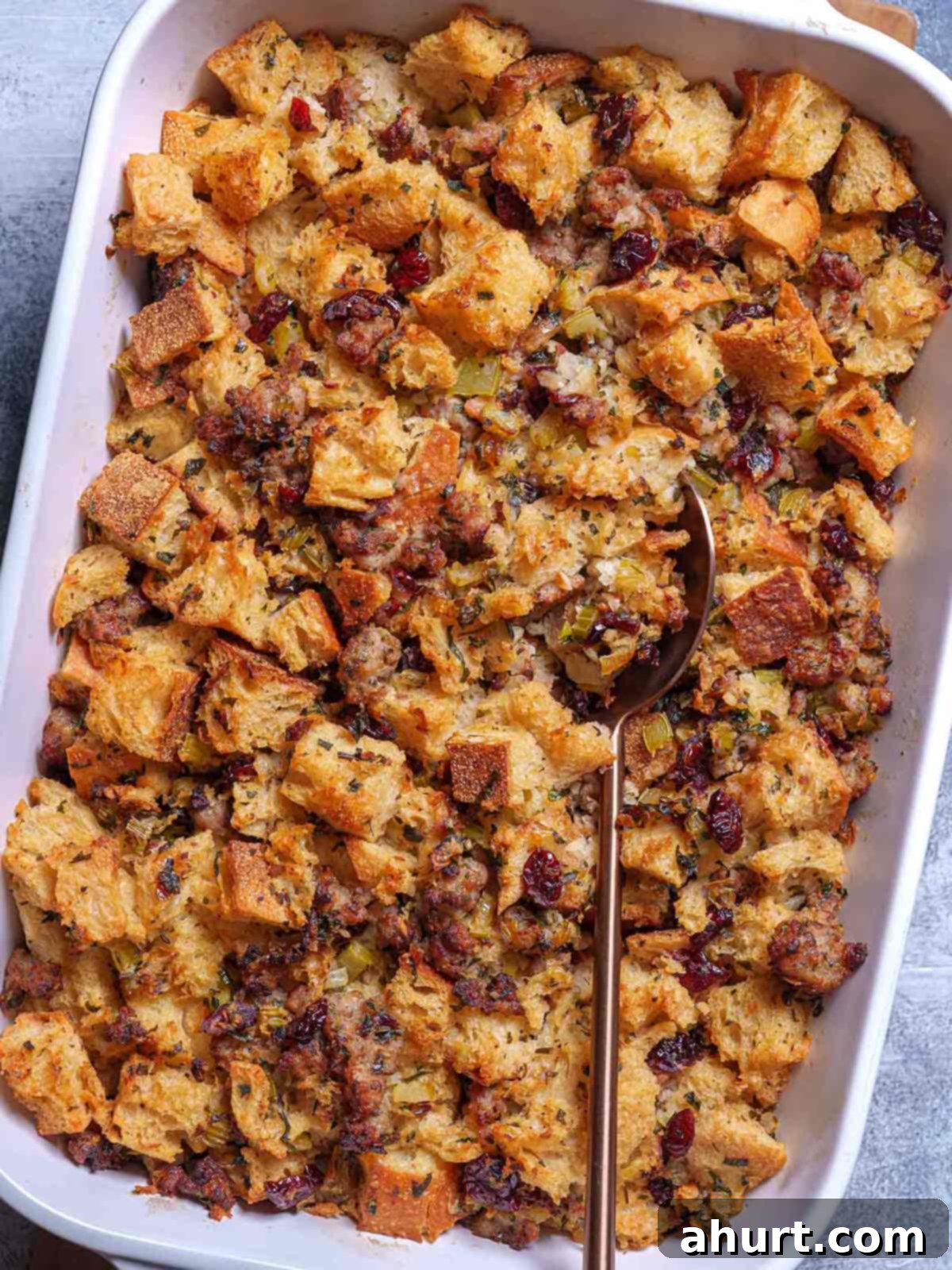 Irresistible Sausage Stuffing 10 A vibrant image of the golden-finished sausage meat stuffing in a white baking tray, accompanied by a yellow spoon, is ready to be enjoyed.