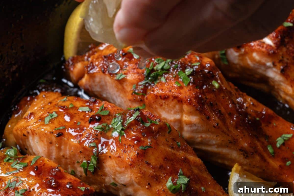 Glazed Honey Garlic Salmon 7 Close-up image of the salmon, ready to be served, with fresh parsley sprinkled on top and drizzled with a squeeze of lemon juice.